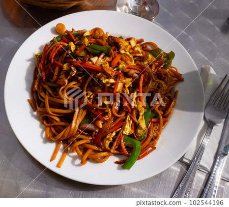 Fried noodle dish with onion, pepper, carrot, meat and egg Fried noodle dish with onion, pepper, carrot, meat and egg 102544196