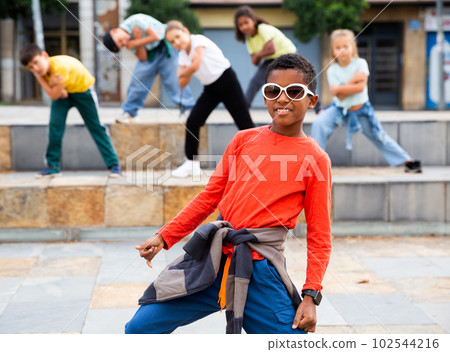 African boy dancing hip-hop with group of tweens on city street African boy dancing hip-hop with group of tweens on city street 102544216