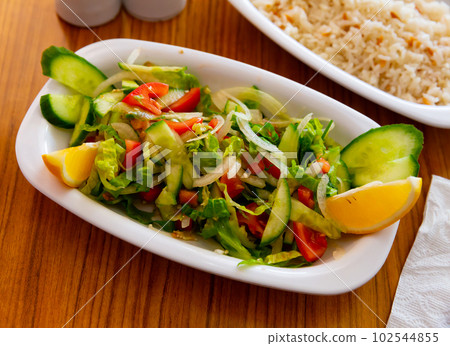 Choban salad from tomatoes, cucumbers, greens, onions with lemon 102544855