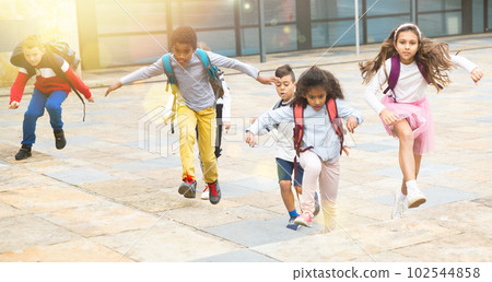 Team of positive schoolchildren running in race in the street 102544858