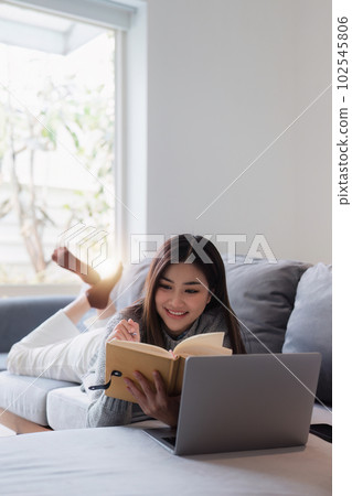Online education, e-learning. Asian woman in stylish casual clothes, studying using a laptop, listening to online lecture, taking notes, online study at home Online education, e-learning. Asian woman in stylish casual clothes, studying using a laptop, listening to online lecture, taking notes, online study at home 102545806