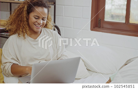 Young woman using laptop on bed at home in the morning. 102545851