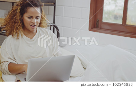 Young woman using laptop on bed at home in the morning. 102545853