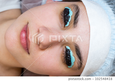 Close-up portrait of a woman on the procedure of lamination and tinting of eyelashes. Permanent makeup. Close-up portrait of a woman on the procedure of lamination and tinting of eyelashes. Permanent makeup. 102548418