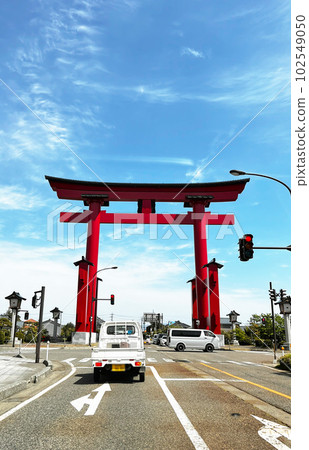 A bright red torii towering over the road 102549050