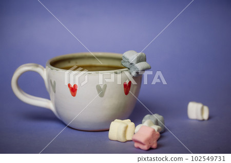 A cup of coffee, cocoa, chocolate with hearts on a lilac violet background. Marshmallows on a table. Cozy still life with hot drink made with love, sweets. February 14, Happy Valentines Day concept. A cup of coffee, cocoa, chocolate with hearts on a lilac violet background. Marshmallows on a table. Cozy still life with hot drink made with love, sweets. February 14, Happy Valentines Day concept. 102549731