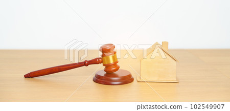 Real Estate Law, Home Insurance, property Tax, Auction and Bidding concepts. small toy house model with gavel justice hammer on desk in courthouse. 102549907