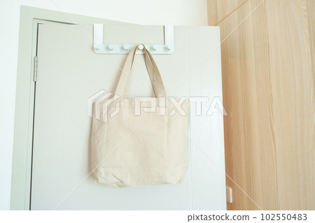 Eco friendly bag hanging on the door. Canvas Shopping tote bag. Zero waste, Reusable, Say No Plastic, Sustainability, World Environment day and Earth day concept Eco friendly bag hanging on the door. Canvas Shopping tote bag. Zero waste, Reusable, Say No Plastic, Sustainability, World Environment day and Earth day concept 102550483