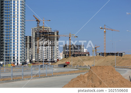 Construction site. Reinforced concrete frame of a multi-storey building and construction cranes. The final stage of construction. Against the background of the blue sky. 102550608