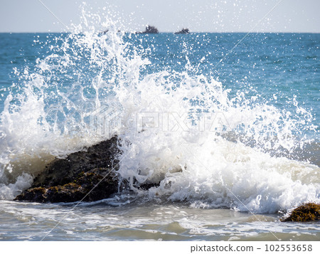 Waves hit rocks on the shore, creating splashes. Waves hit rocks on the shore, creating splashes. 102553658