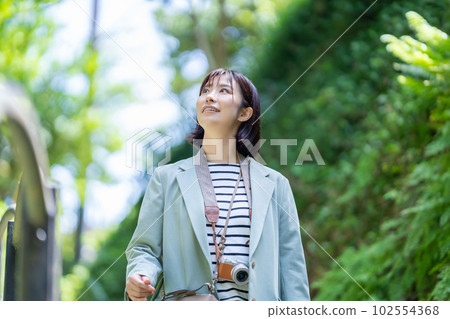 A woman walking in fresh greenery A woman enjoying sightseeing A woman walking in a tourist spot A woman traveling on a holiday 102554368