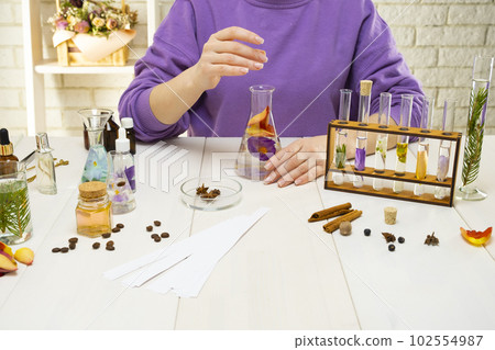 Preparation of perfumes from natural ingredients, aromatherapy. Fresh flowers and natural ingredients in chemical test tubes and flasks 102554987