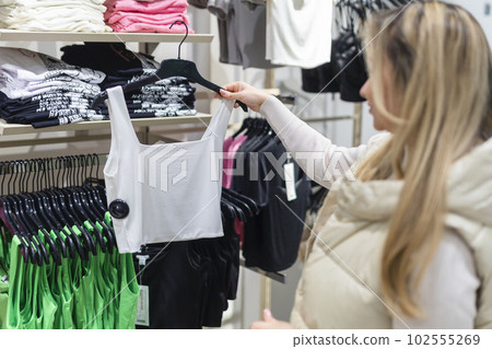 Happy young woman buying new clothes in store. Sale shopping fashion and people concept Happy young woman buying new clothes in store. Sale shopping fashion and people concept 102555269