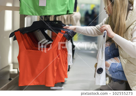 Happy young woman buying new clothes in store. Sale shopping fashion and people concept 102555273