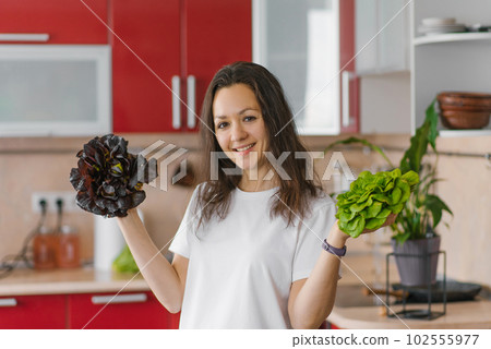 Young happy vegetarian nutritionist woman holds two types of salad in her hands, natural organic food, healthy food at home 102555977