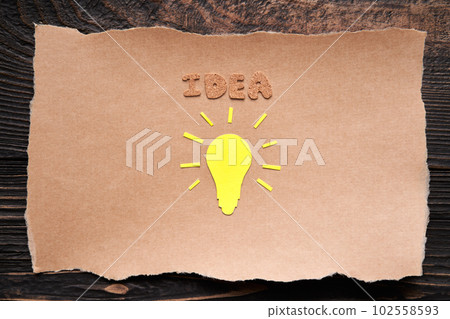 Creative idea and inspiration concept with paper light bulb on ripped piece of craft paper 102558593