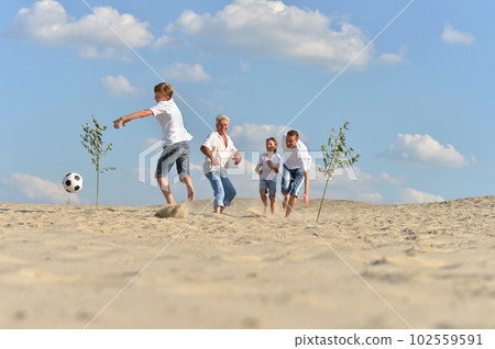 Family playing football on a beach in summer day 102559591