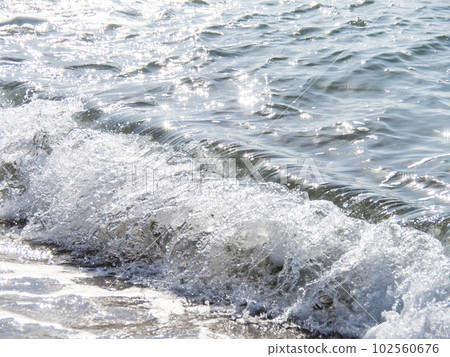 The waves crashing on the sandy beach and the surface of the sea that reflects the sunlight. The waves crashing on the sandy beach and the surface of the sea that reflects the sunlight. 102560676