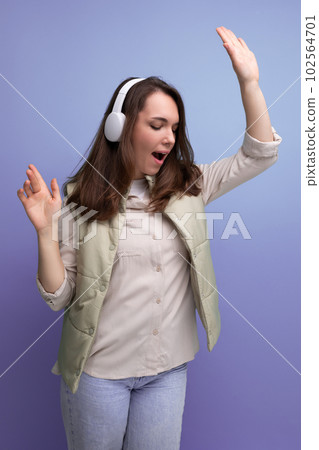 energetic young brunette woman relaxing to music using headphones and mobile phone 102564701