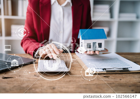 Buying a home or insurance deal, an insurance agent pointing a pen to those interested in renting a house, a contract, signing an Home buying agreement in office Buying a home or insurance deal, an insurance agent pointing a pen to those interested in renting a house, a contract, signing an Home buying agreement in office 102566147