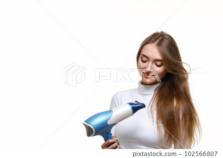 Portrait of attractive cheerful girl drying long hair 102566807