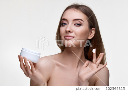 beautiful smiling young woman applying skin care cream on her face 102566815
