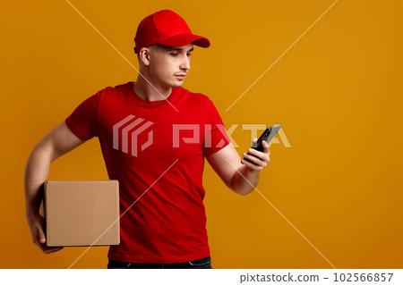 Delivery man employee in red cap, t-shirt holding empty cardboard box and phone 102566857
