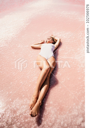 Woman pink salt lake. She lies in a white bathing suit. Wanderlust photo for memory 102566976