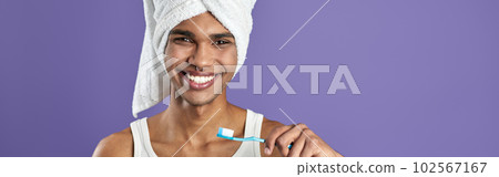 Young transgender man brushing teeth isolated on purple background portrait Young transgender man brushing teeth isolated on purple background portrait 102567167