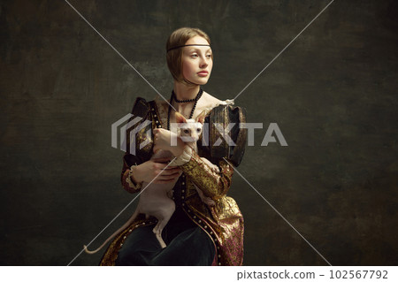Portrait of beautiful young girl in elegant clothing over dark vintage background posing with sphynx cat. Lady with ermine remake 102567792