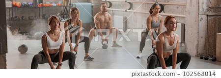 Group of people exercising with kettlebells at gym Group of people exercising with kettlebells at gym 102568014