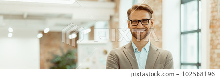 Smiling man standing in a coworking space and clasped his hands Smiling man standing in a coworking space and clasped his hands 102568196