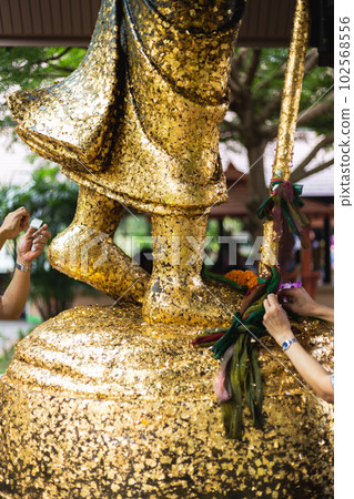 People attached gold leaf to the statue of Buddha People attached gold leaf to the statue of Buddha 102568556