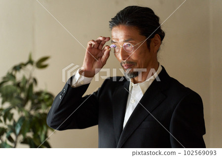A cool senior man looking into the distance while touching his glasses A cool senior man looking into the distance while touching his glasses 102569093