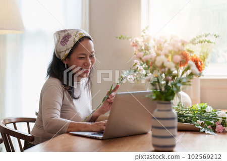 Startup, small business, flower shop. Older florist putting a flower on a vase 102569212