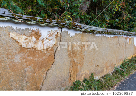 An old earthen wall with peeled plaster An old earthen wall with peeled plaster 102569887