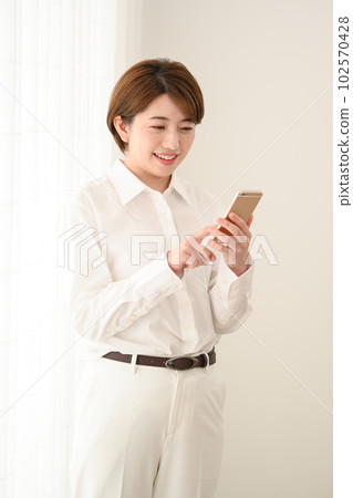 A woman watching a smartphone at the window side A woman watching a smartphone at the window side 102570428