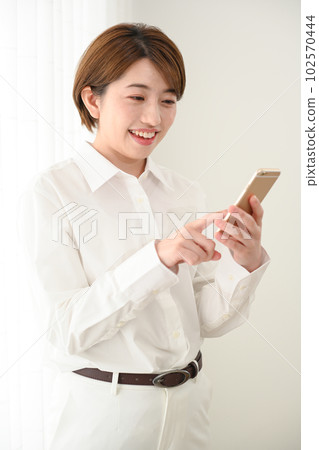 A woman watching a smartphone at the window side 102570444