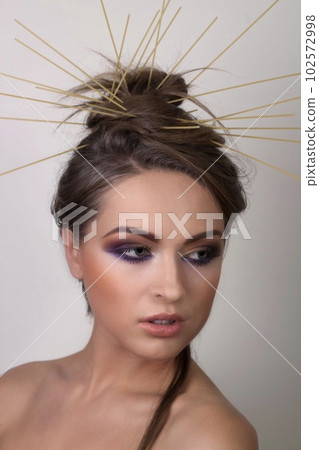 Portrait of a beautiful smiling girl with a bright make-up with pasta decorations Portrait of a beautiful smiling girl with a bright make-up with pasta decorations 102572998