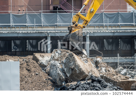 Heavy machinery handling large debris at a demolition site 102574444