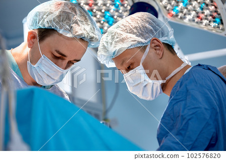 Faces of surgeons close-up during a complex and intense operation, doctors save the patient's life, teamwork of surgeons 102576820