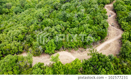 Unrecognisable mountain bikers riding on a beautiful winding single track, aerial view, Massa Marittima, Tuscany, Italy Unrecognisable mountain bikers riding on a beautiful winding single track, aerial view, Massa Marittima, Tuscany, Italy 102577231