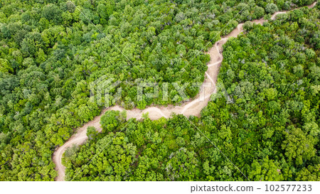 Unrecognisable mountain bikers riding on a beautiful winding single track, aerial view, Massa Marittima, Tuscany, Italy 102577233