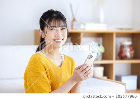 一個操作智能手機的年輕女子 一個操作智能手機的年輕女子 102577960