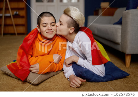 Loving lesbian couple posing together with rainbow multicolored flag Loving lesbian couple posing together with rainbow multicolored flag 102578576