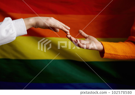 Hand reaching other hand over rainbow pride flag. Lgbtq intersex rights concept Hand reaching other hand over rainbow pride flag. Lgbtq intersex rights concept 102578580