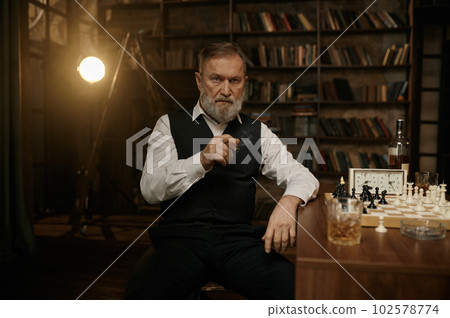 A chess player smoking cigar and planning strategy of game 102578774