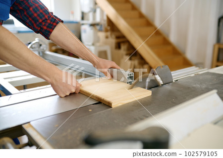 Close-up view on carpenter cutting wooden board on circular saw 102579105