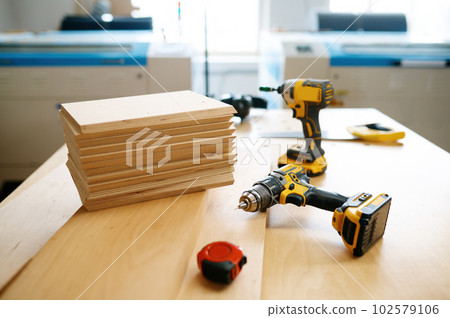 Electric drill, ruler and wooden board at carpenter workplace 102579106