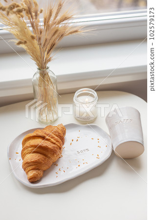 White glass and a plate on which there is a croissant made of clay with an inscription, handmade. 102579173